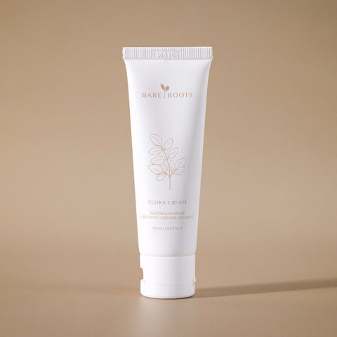 Flora Cream tube standing upright on a beige background