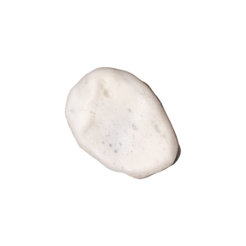 Close-up of Gentle Foaming Cleanser’s creamy foam texture on light surface.