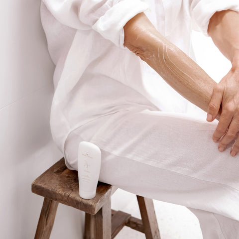 Gentle Cleansing Milk tube resting on a chair beside a seated woman