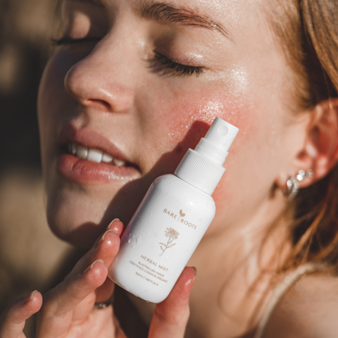Woman applying herbal mist to her face with a blurred background