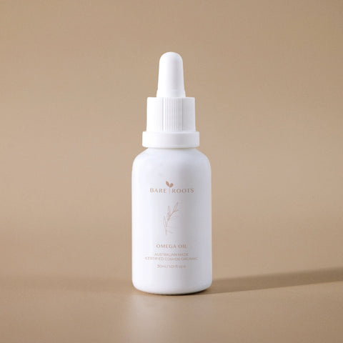 Bare Roots Omega Oil bottle standing upright on a neutral beige background, highlighting its minimalist design.