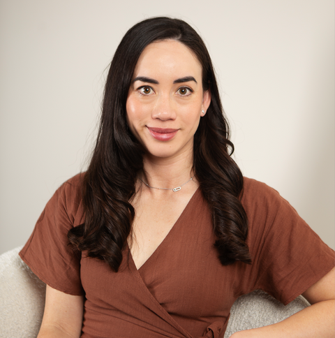 Woman wearing a brown top against a plain background