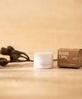 Bare Lips lip balm container and packaging on a beige background