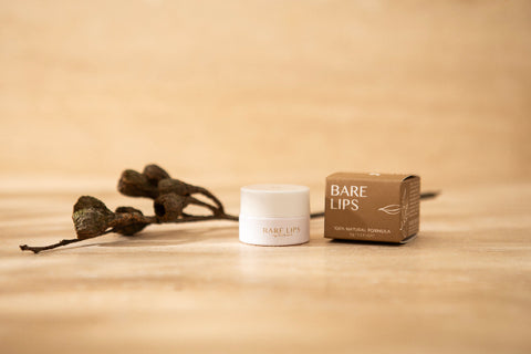 Bare Lips lip balm container and packaging on a beige background