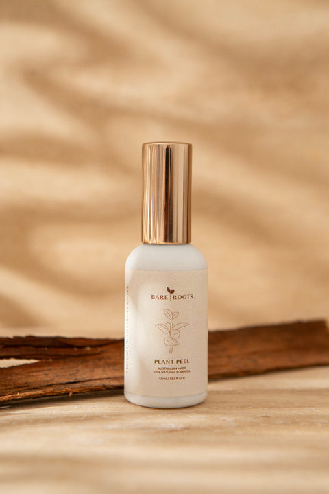 Skincare bottle labeled 'bare roots' on a wooden surface with a natural background