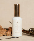 White bottle with gold cap on a beige background with natural elements
