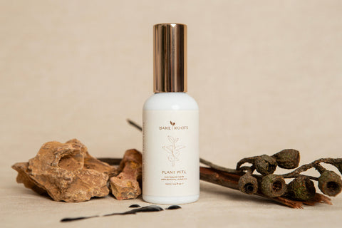 White bottle with gold cap on a beige background with natural elements