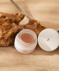 Bare lips open jar against earthy background