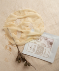 flat lay camellia sheet mask out of packet against beige fabric backdrop