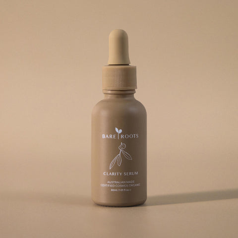 Clarity Serum bottle standing upright on a soft beige backdrop