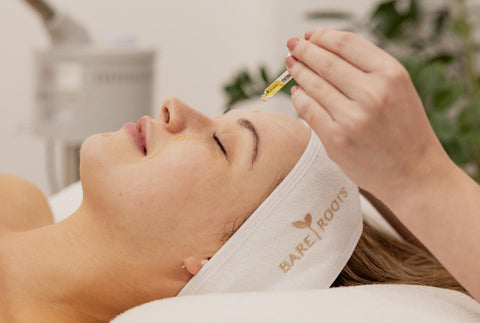 Omega Oil being gently applied to a woman's face during a facial, illustrating its nourishing, professional use.