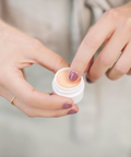 Woman gently applying Bare Lips balm to her lips using her finger.