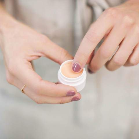 Woman gently applying Bare Lips balm to her lips using her finger.