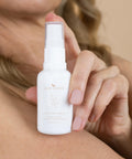 Woman holding the Curative Serum bottle near her face.