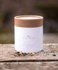 Bare Roots Wholesome Beauty Tea pouch on a wooden surface with loose tea leaves sprinkled around.