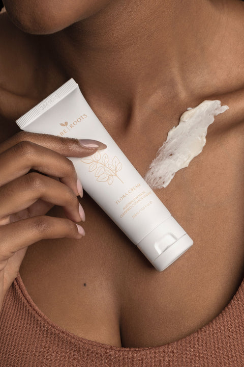 Person holding a tube of skincare product on their skin with a visible application mark.