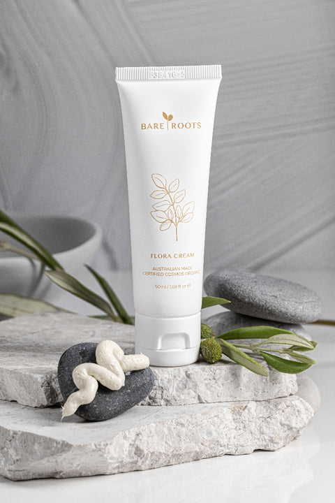 Bare Roots Flora Cream tube on a stone surface with greenery