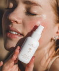 Woman applying herbal mist to her face with a blurred background