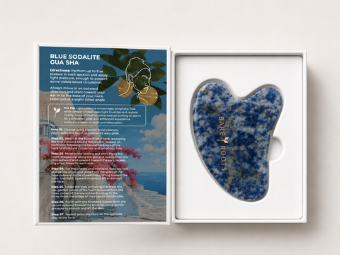 A blue and white marbled gua sha massage tool inside a white presentation box next to its printed packaging insert.