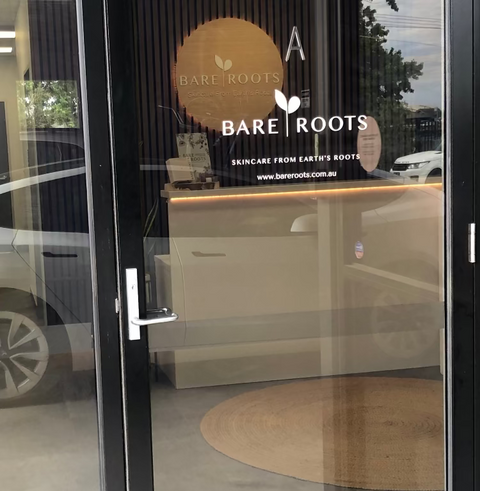 Glass door with 'Bare Roots' skincare store logo and interior view.